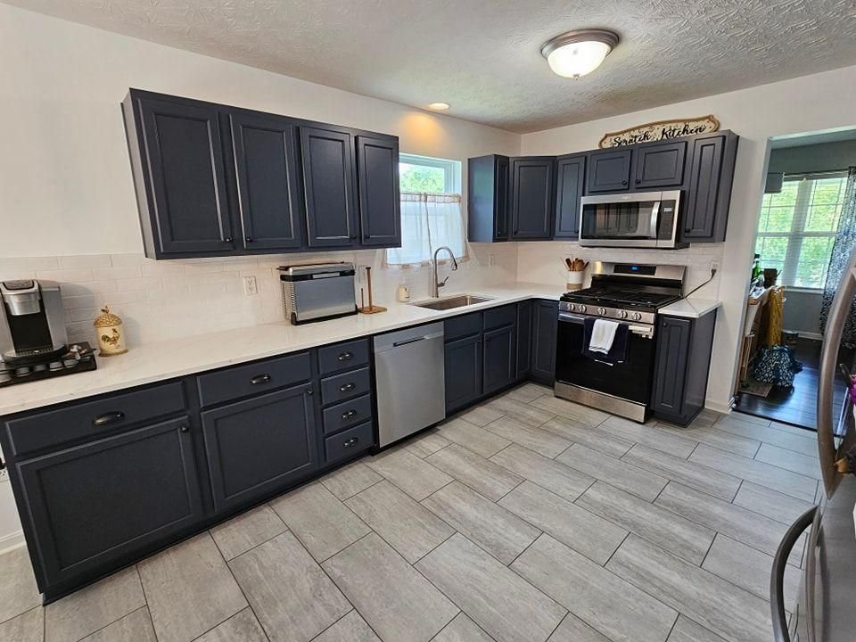 Navy blue refinished kitchen cabinets with stainless appliances