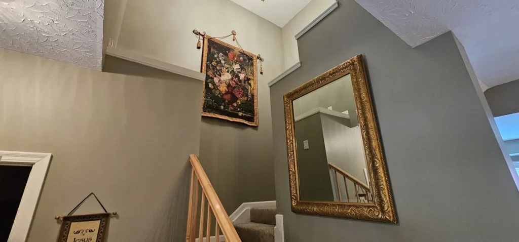 Gray stairwell walls with white trim and natural-wood railing in Cold Spring, Kentucky.