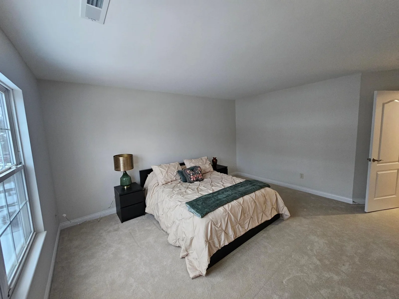 Completed bedroom with light neutral walls, white trim and a tray ceiling.